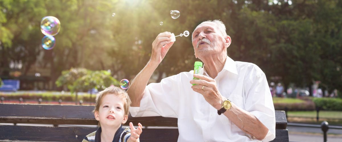 grandfather blowing soap bubbles to his grandchild